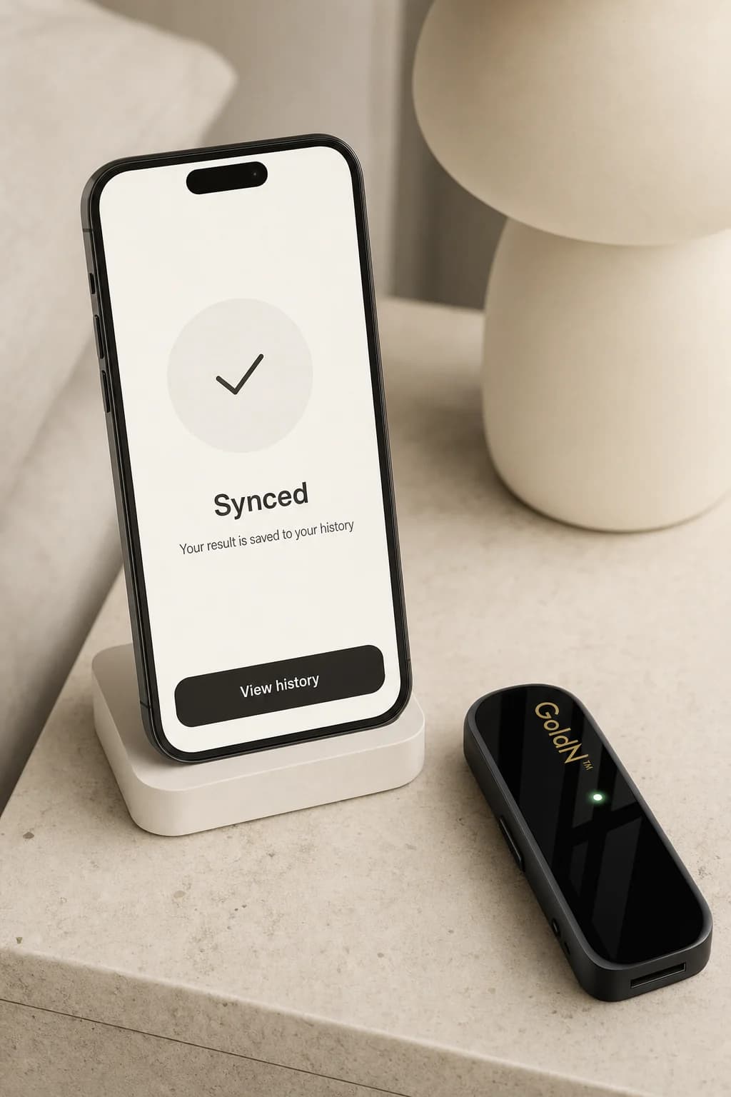 A phone on a stand showing a Synced confirmation next to the GoldN Companion