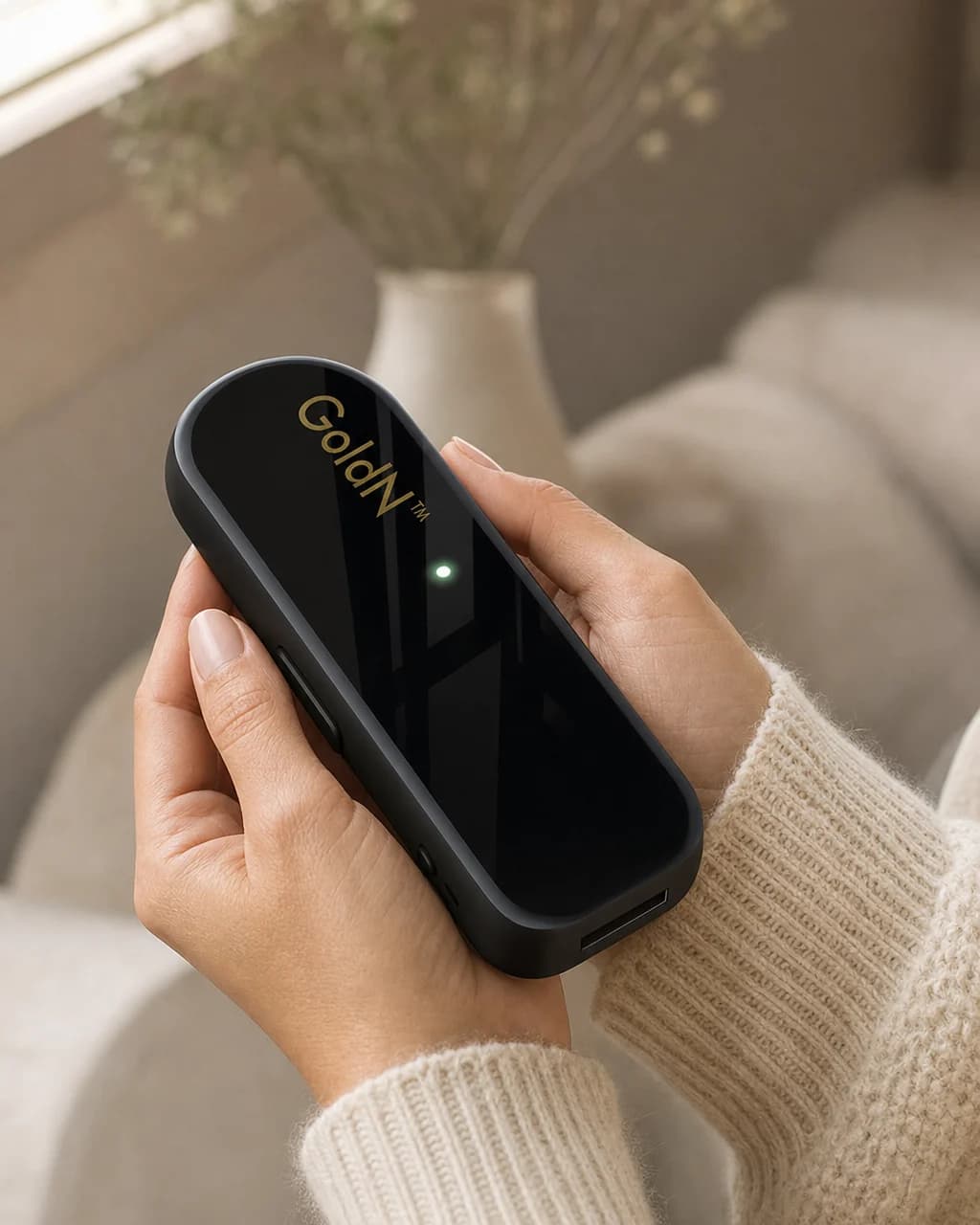 Hands holding the glossy black GoldN Companion at home